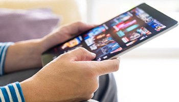 a person on a tablet scrolling through a streaming site
