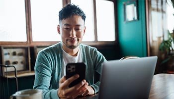 a person on looking at something on their phone in front of their laptop