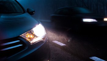 a car's headlights driving at night in the rain