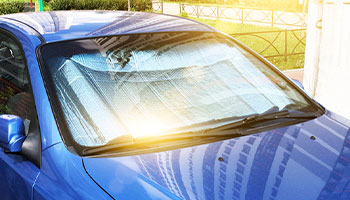 a parked car in the sun with a protective reflector to prevent sun damage